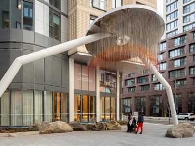 A circular art piece with two legs stands at the entry of a building. 