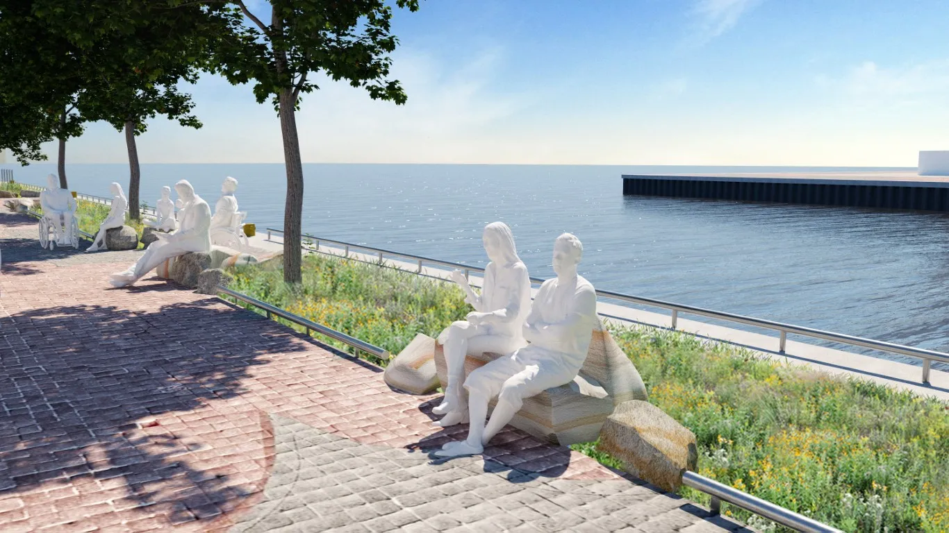 A scenic waterfront promenade with white human figures sitting on large stones, integrated into the landscape design. The figures overlook Lake Ontario, with native plants, trees, and a toe rail lining the path.