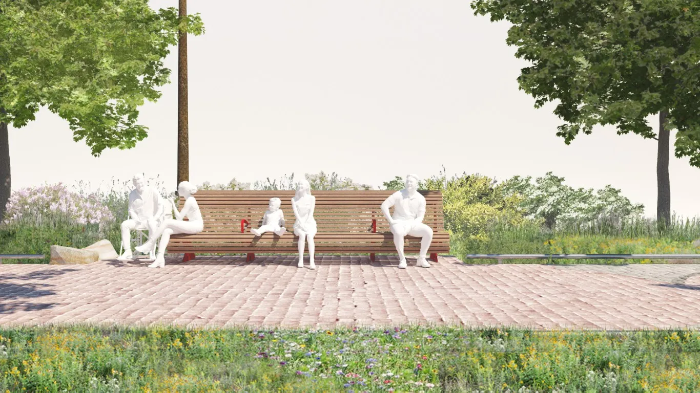 A wooden bench along the Water's Edge Promenade is occupied by several white sculpted human figures, including a child and adults. The bench is set on a cobblestone surface surrounded by wildflowers and trees, with companion seating space visible beside it.