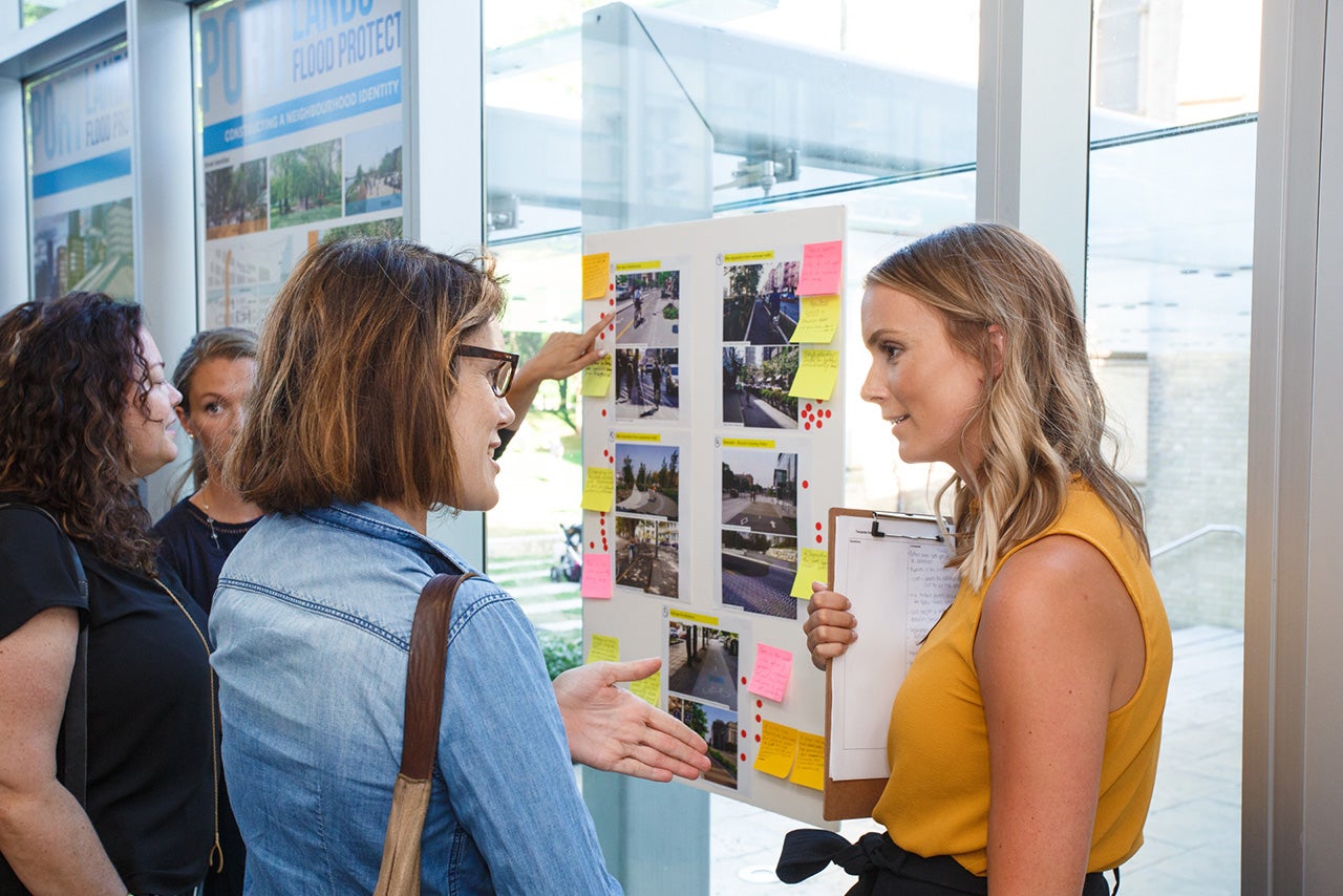 people standing and talking next to public meeting display boards