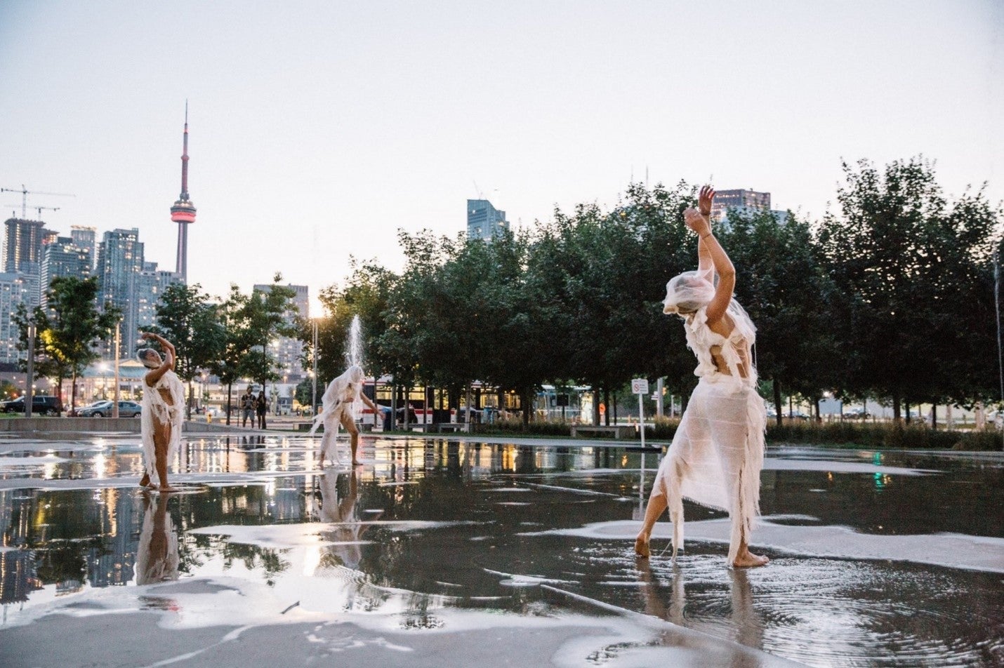dancers performing in the splash pad area of an urban park