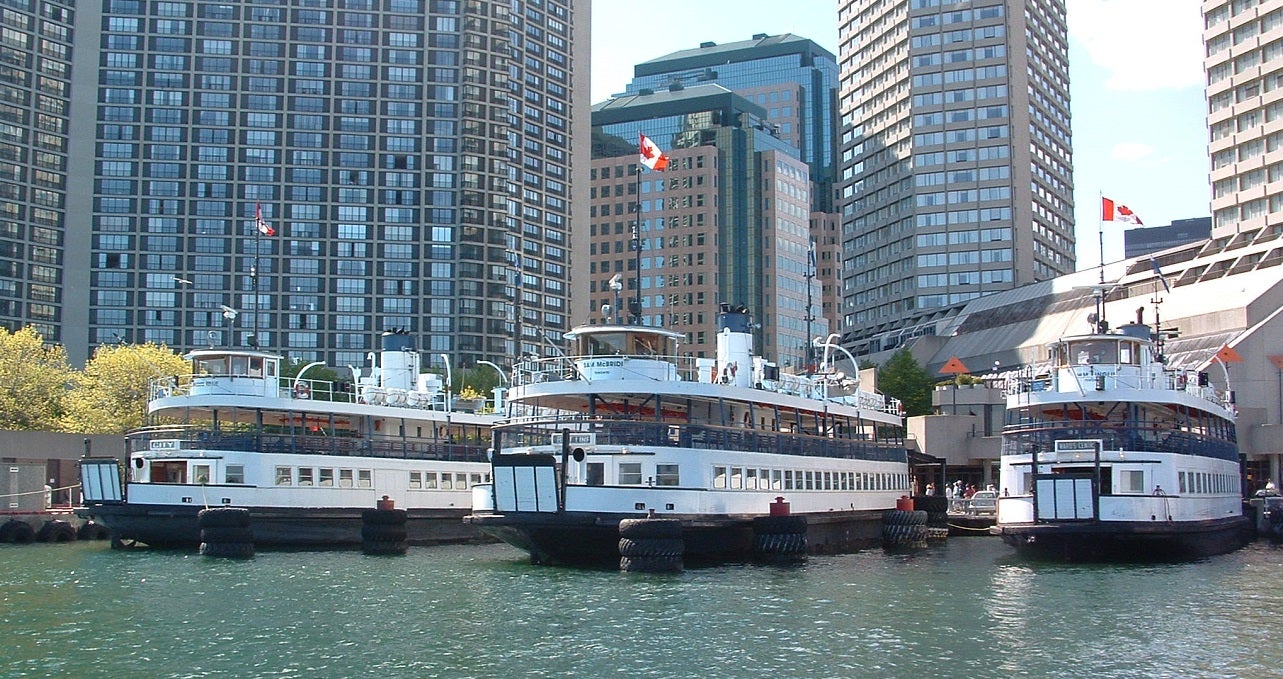 three ferry boats with buildings in the background