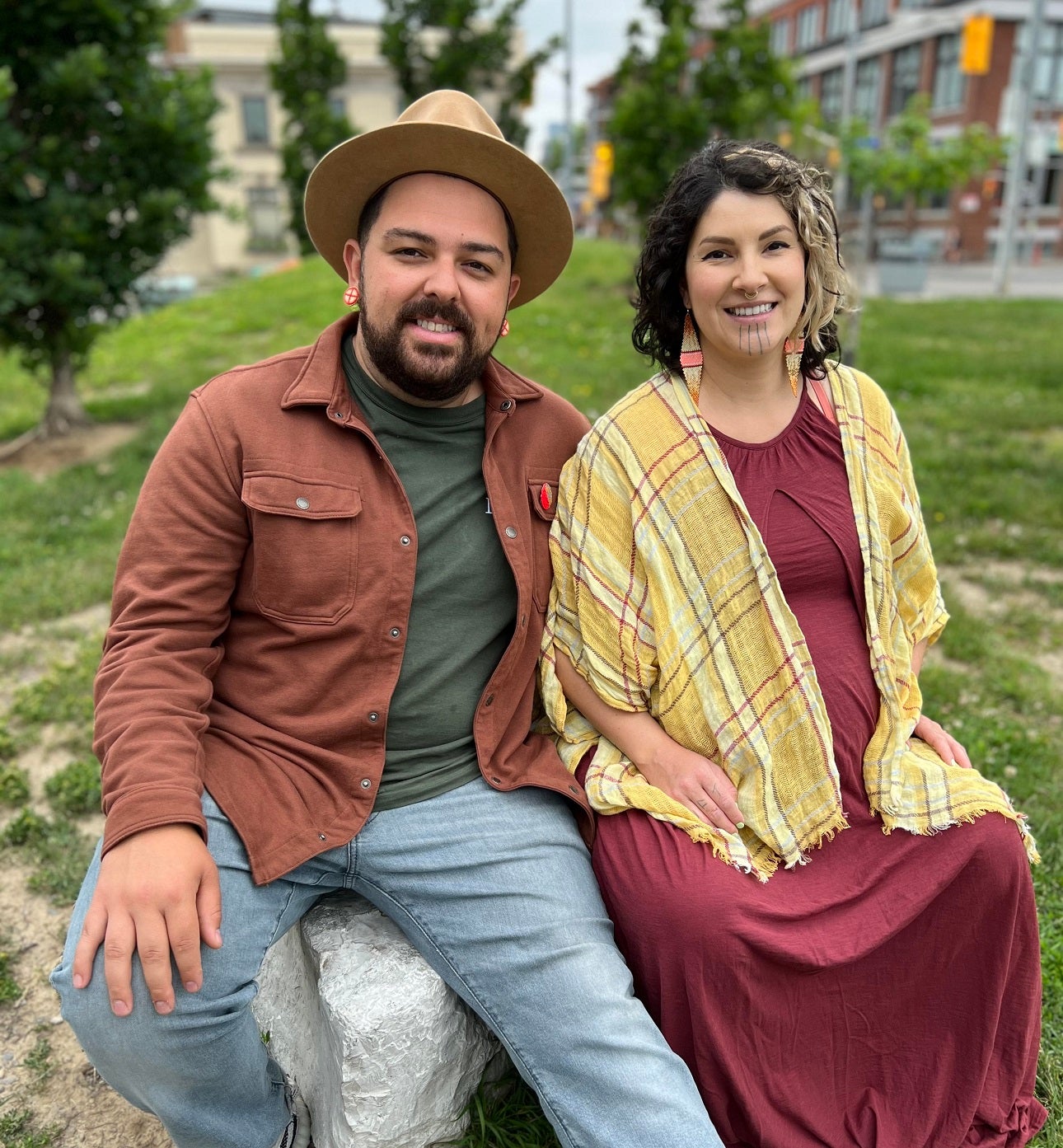 two people posing in a park and sitting on a rock