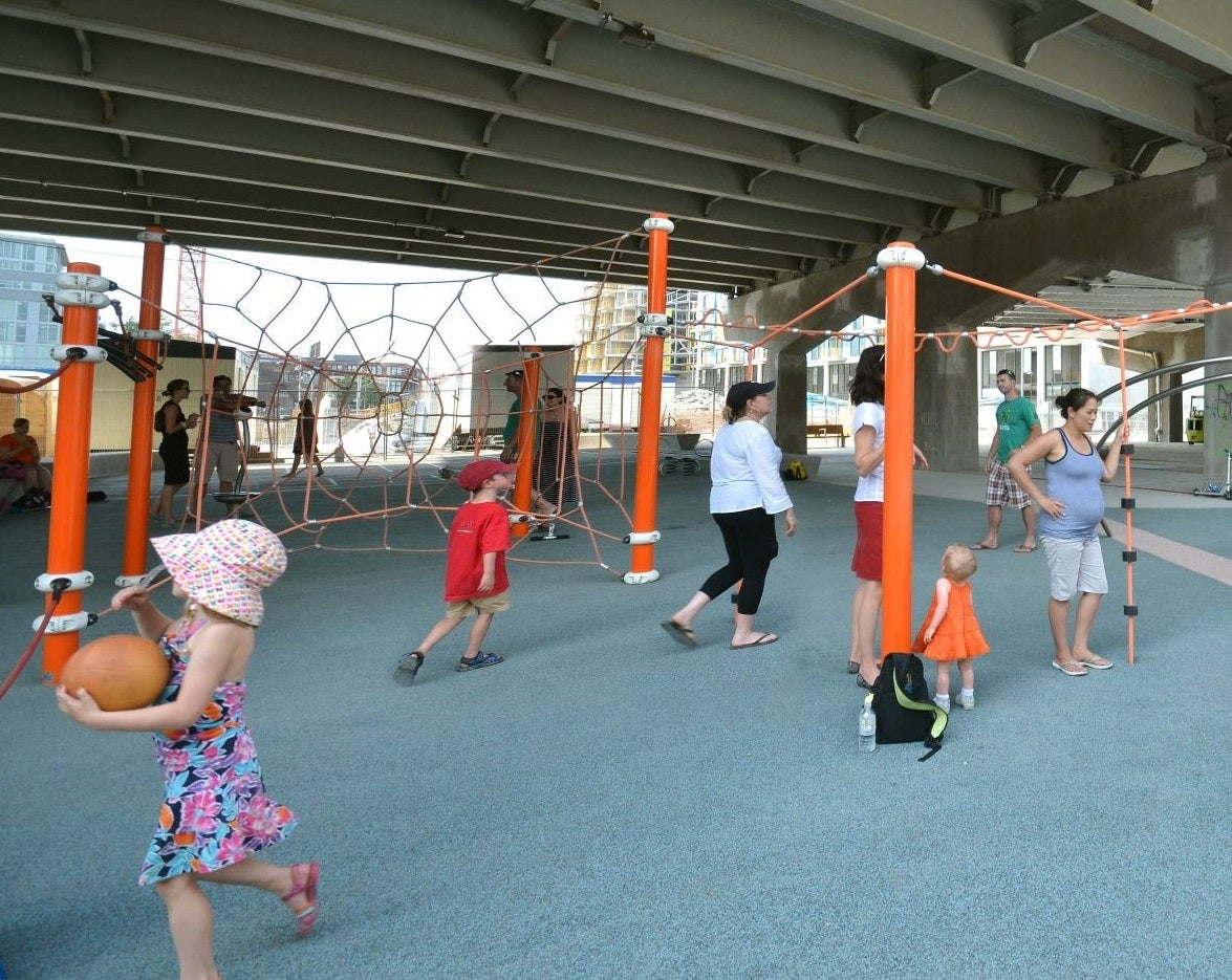 children and adults playing and enjoying the playground in an urban park