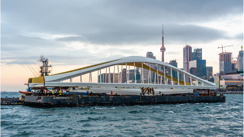 A bridge on a barge with Toronto's skyline in the background.