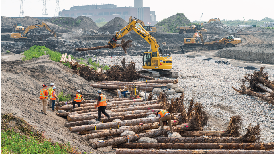 A construction crew on a job site with excavators in the background.