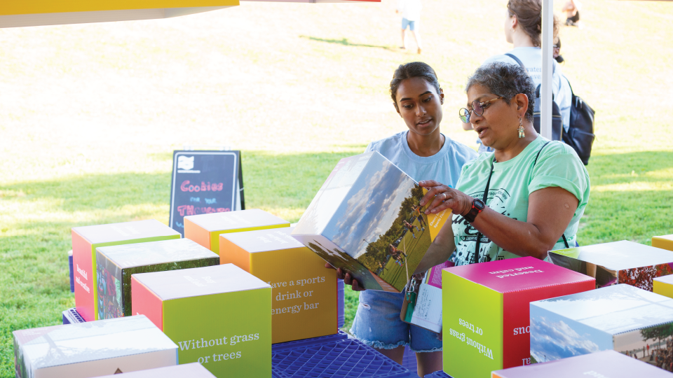 Two people reading informational materials at a pop-up booth in a park.