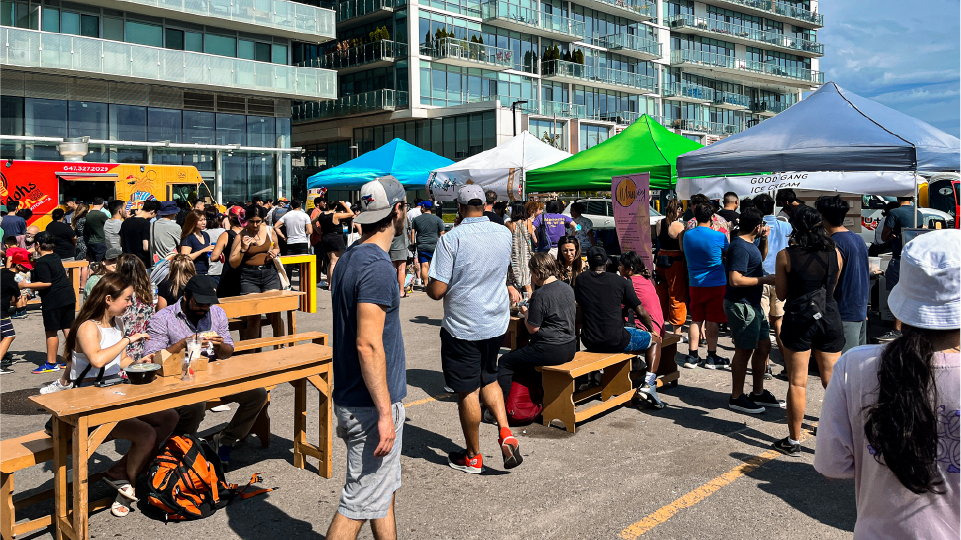 A crowd of people at an outdoor food market. 