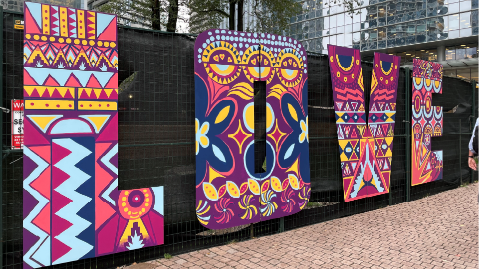 Six-foot tall wooden letters spelling out 'LOVE" mounted on construction fencing