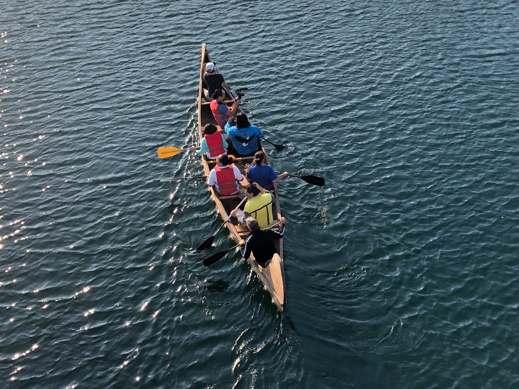 Eight people in a canoe on open water.