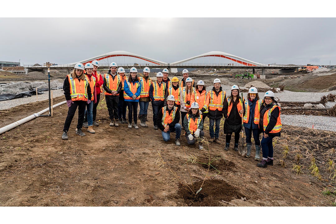 A group of people in safety equipment on a construction site smile together.