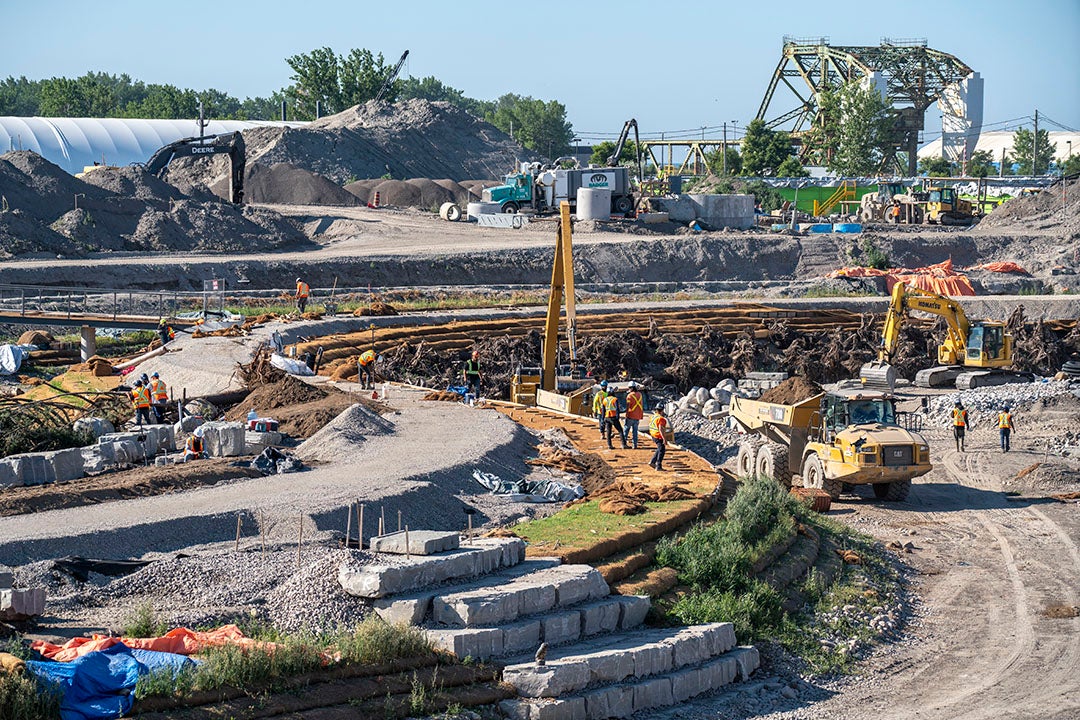 The bank of a new river curves through an excavated area. There is no water in the river yet.