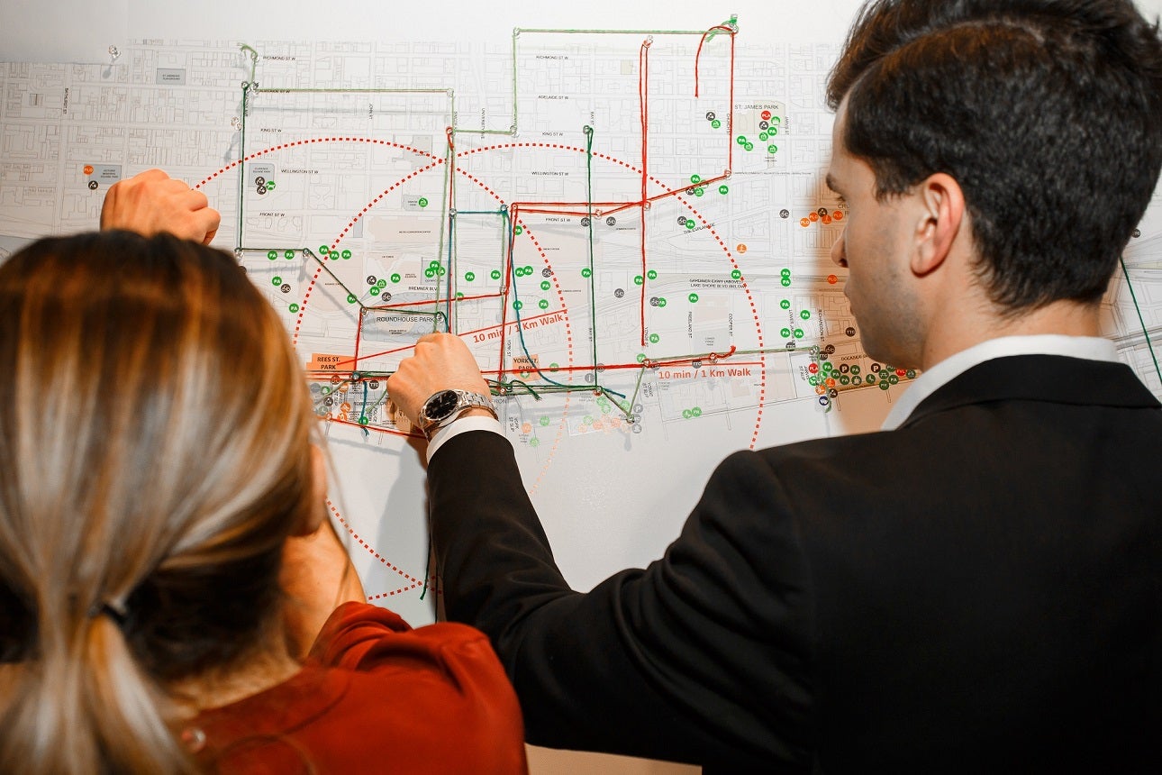 Two people pointing to an area on a wall map