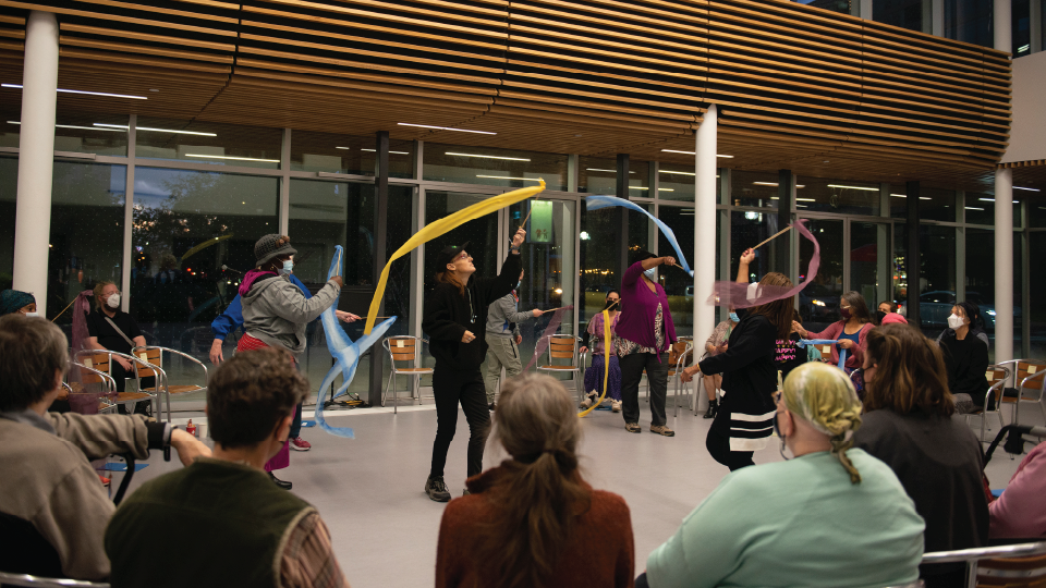 people gathered around watching an outdoor performance with ribbons