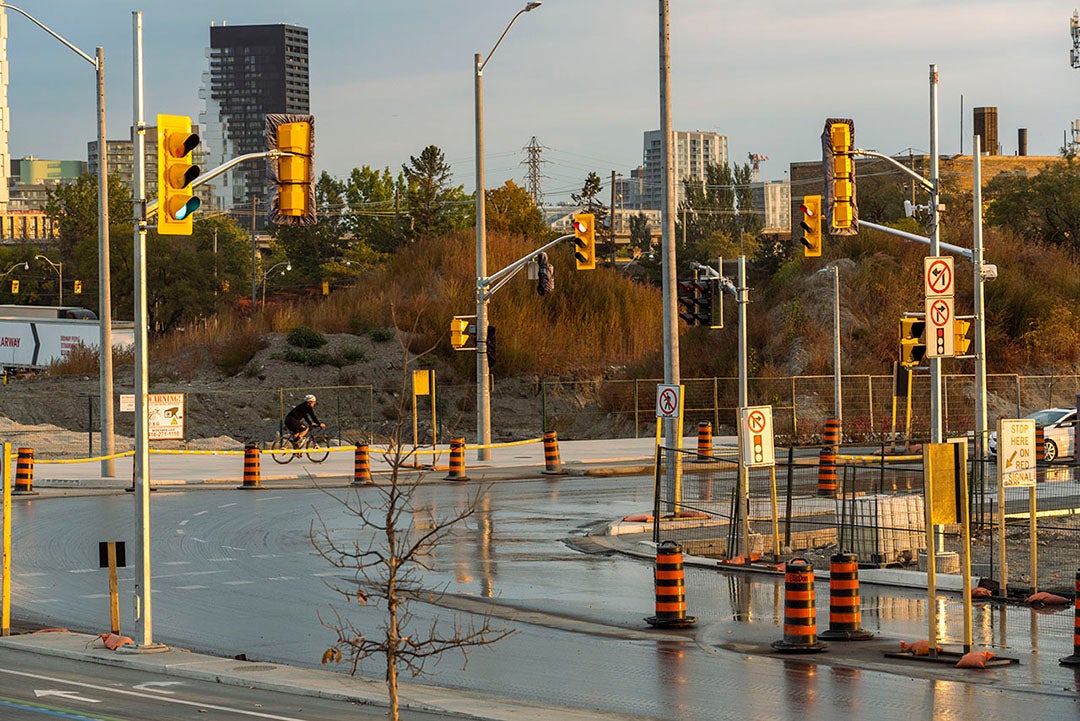 Two roads next to a construction site with construction pylons and signs. 