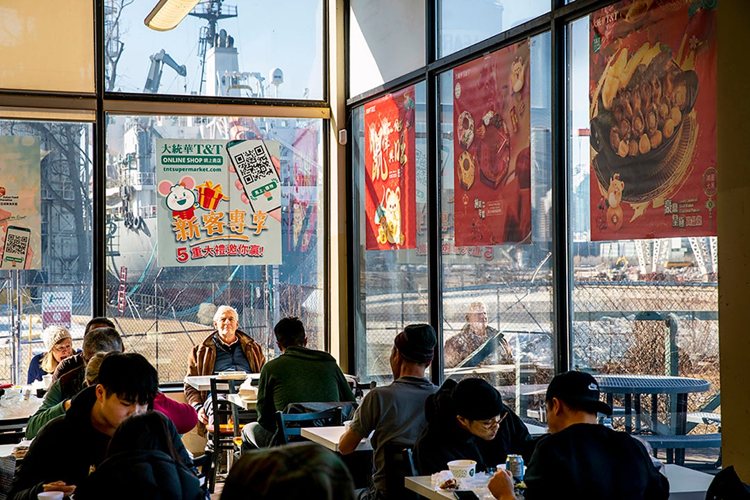 Patrons sit inside a food court inside a grocery store. 