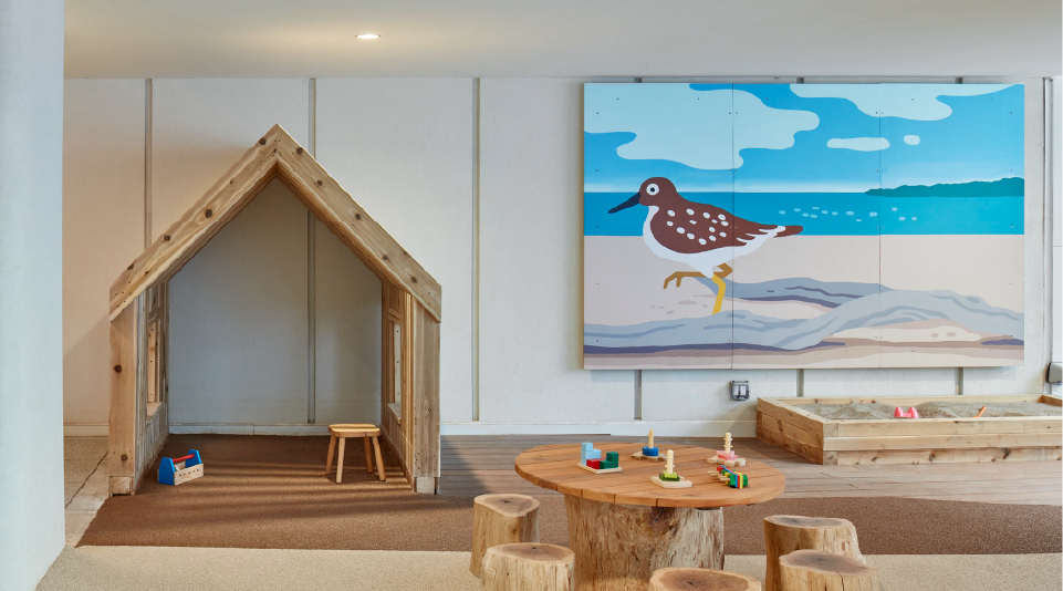 A children's play area with wooden furniture and a bird mural.