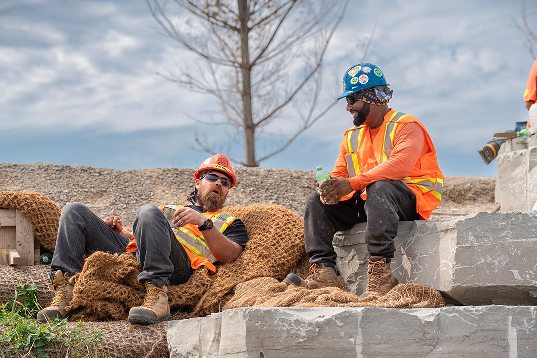 Two construction workers take a break on site and engage in conversation. 