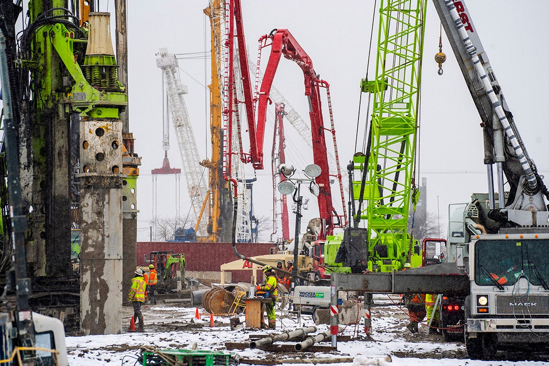 Large machines and earth trucks in a construction site.