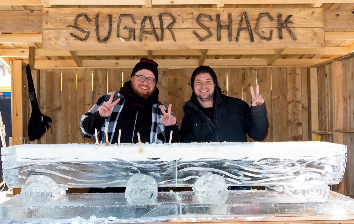 two people at an outdoor booth in front of large block of ice