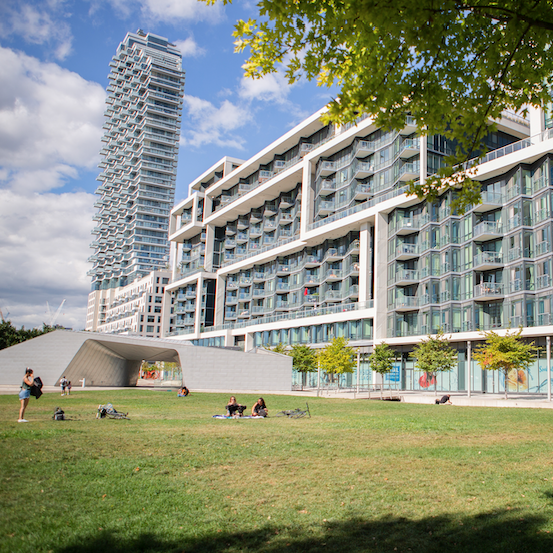 People on a park lawn with a residential building in background.