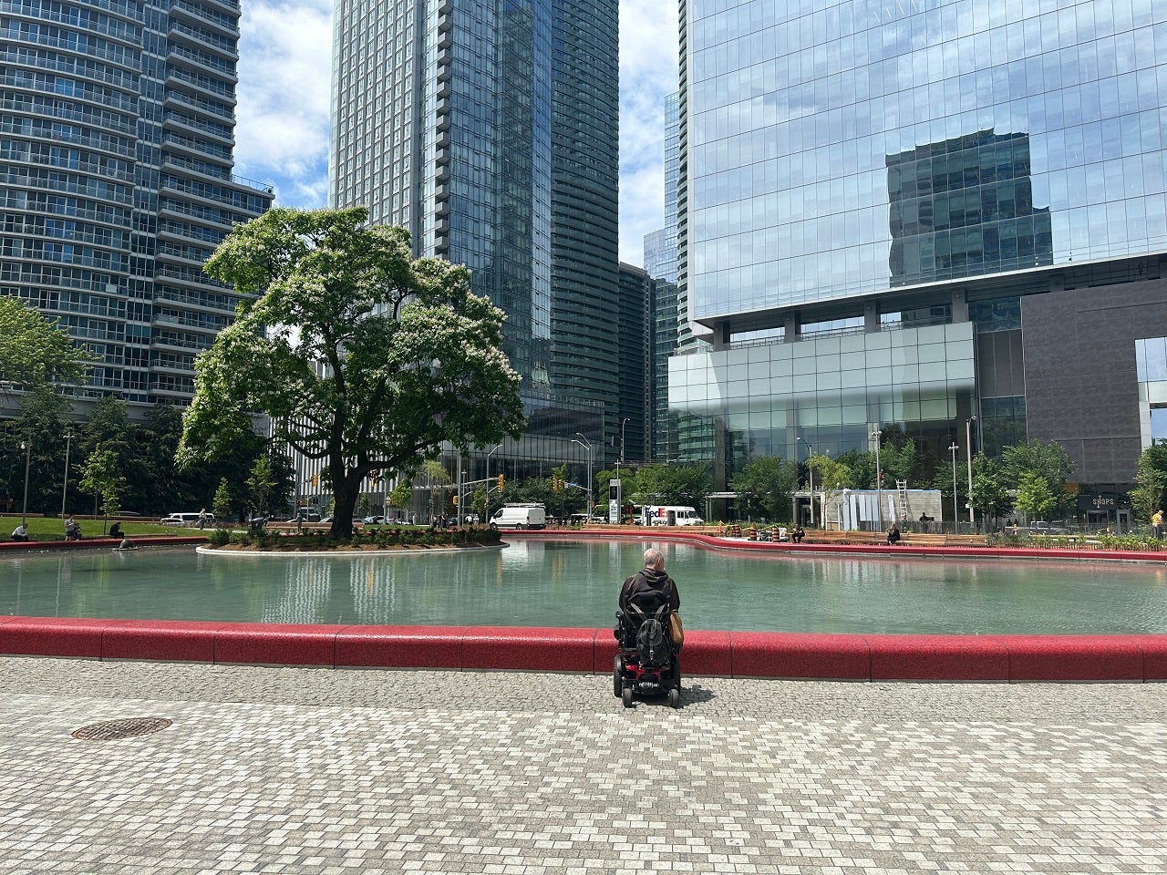 person in a wheelchair next to a red tiled pond