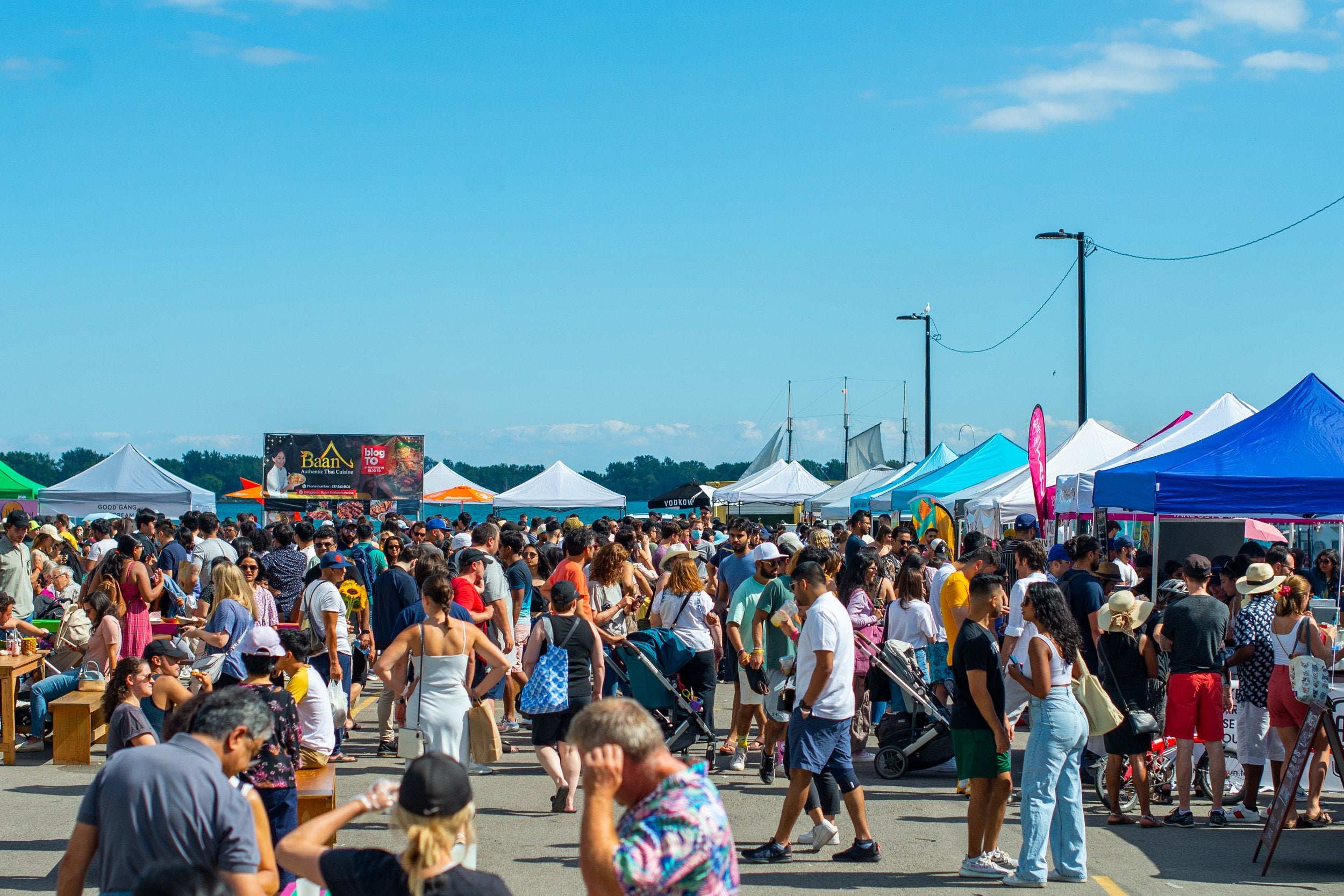 A crowded outdoor food market with vendor tents.