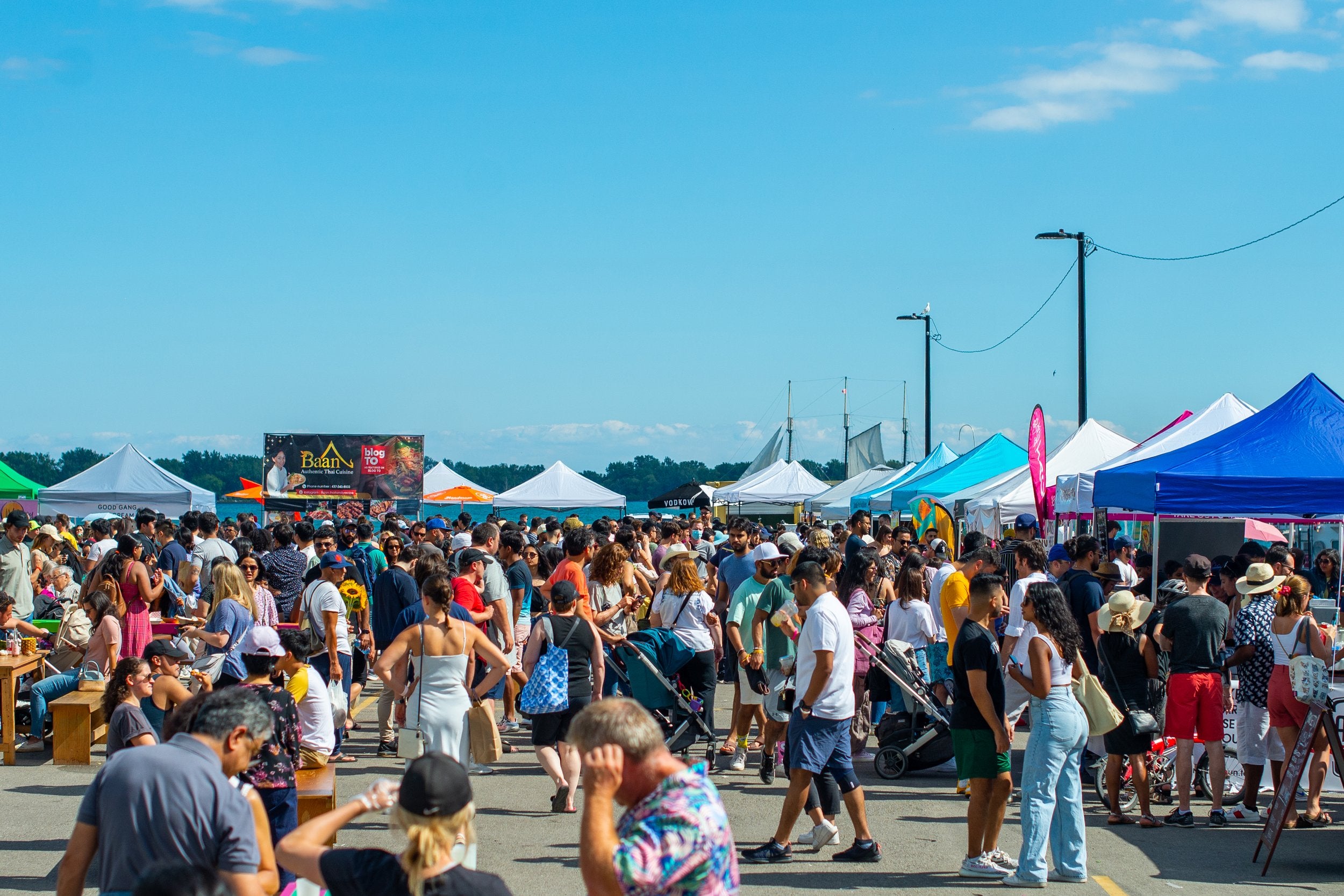 A crowded outdoor food market with vendor tents. 