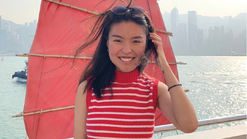 A woman smiling facing the camera. Downtown skyline in background. 