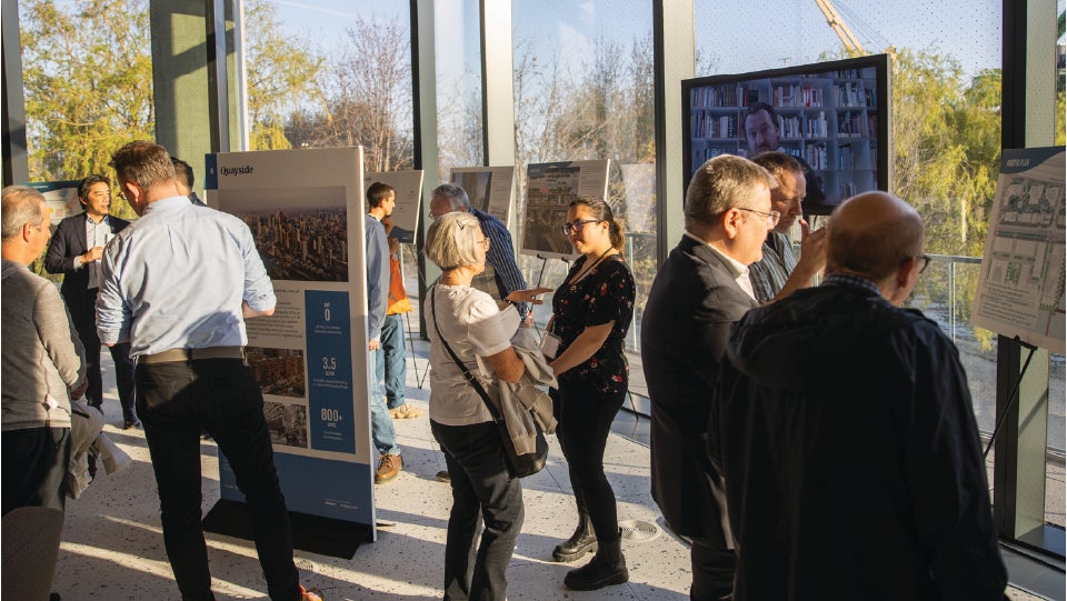 People talking at a public open house with display boards.