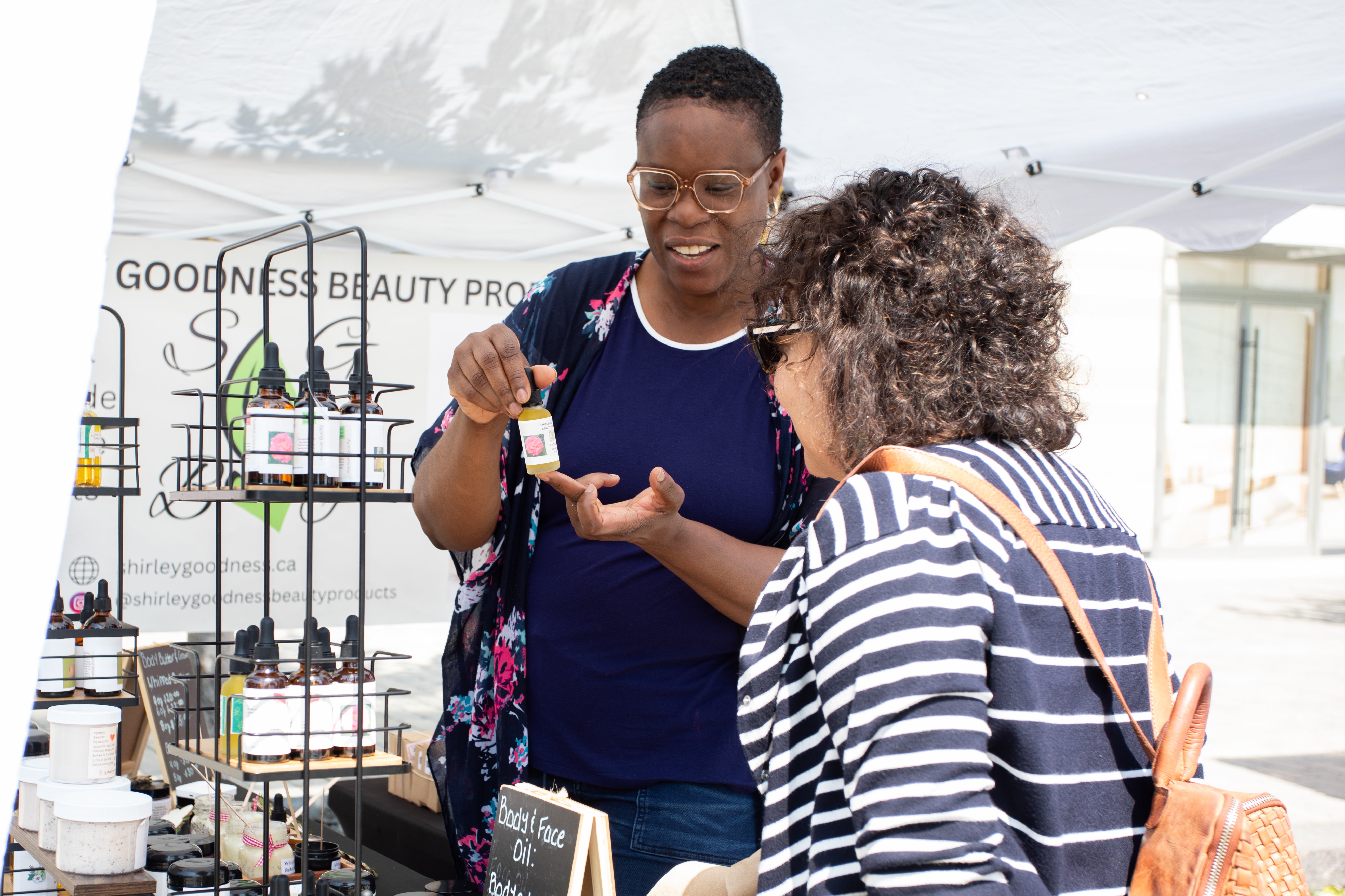 A market vendor shows a product to a customer.