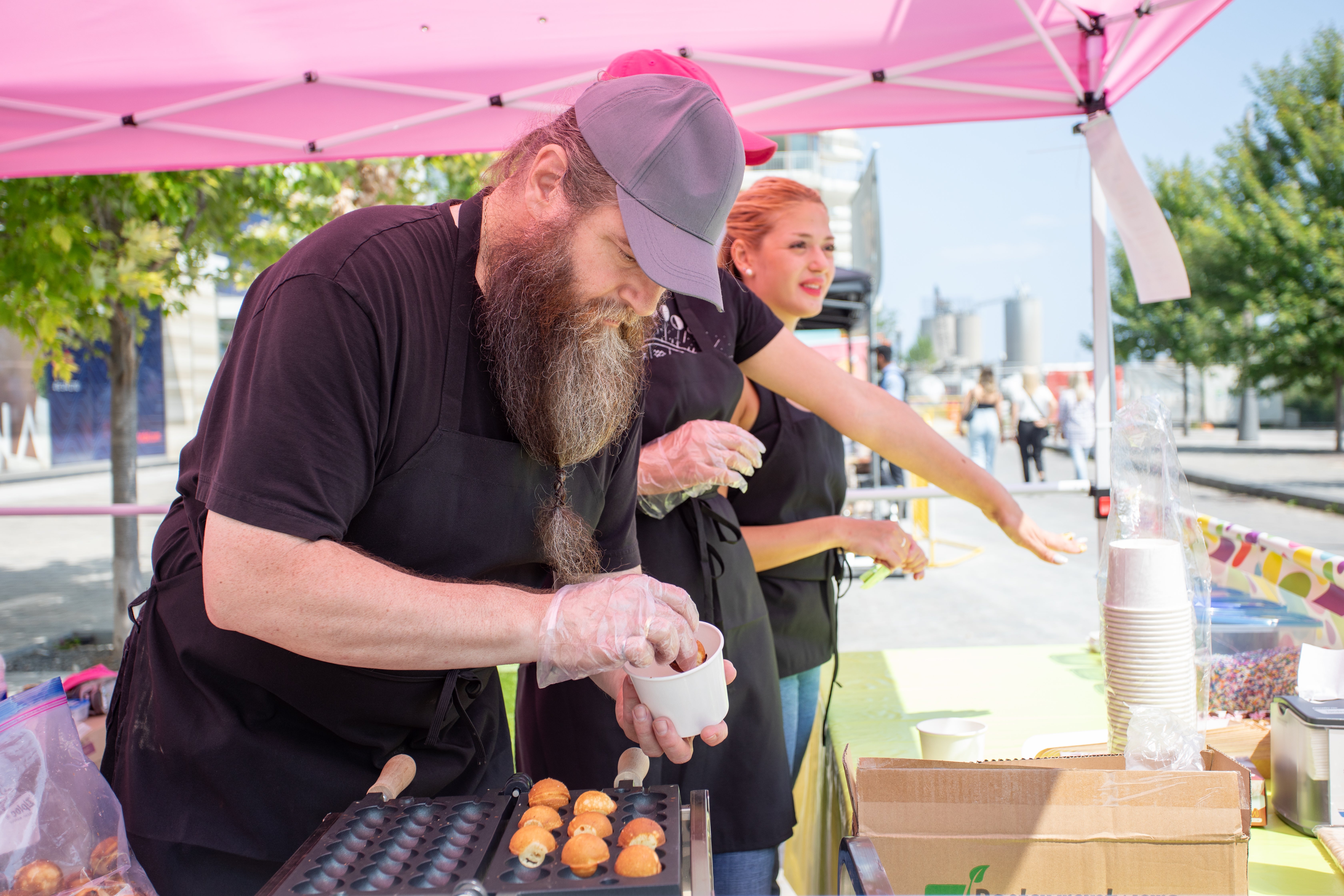 A vendor at a market creates food item for public.