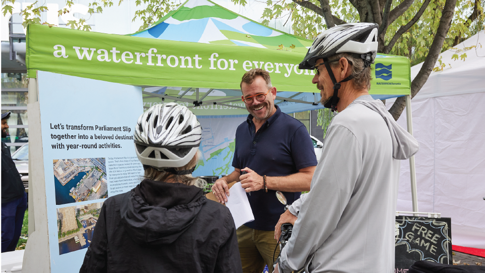 Two cyclists talking to a Waterfront Toronto staff members at an outdoor festival. 
