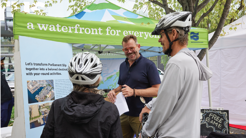Two cyclists talking to a Waterfront Toronto staff members at an outdoor festival.