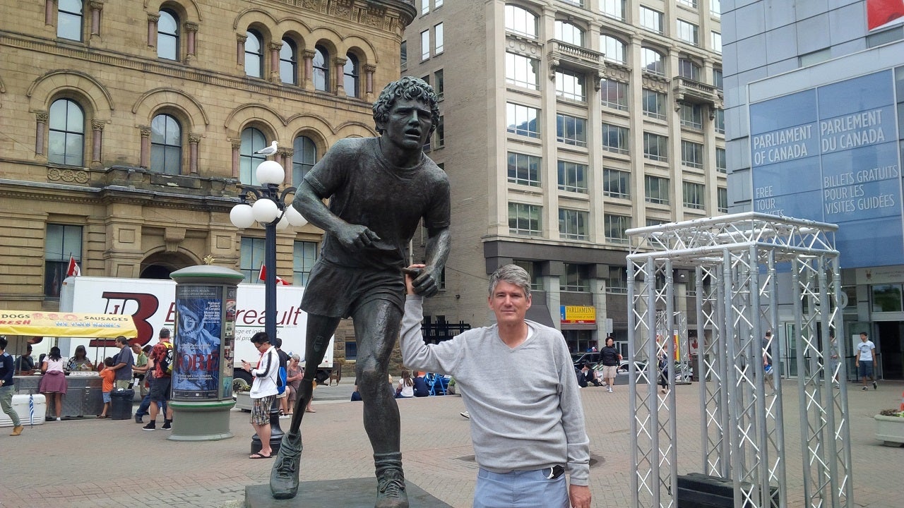 man standing next to a statue of Terry Fox