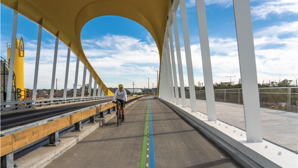 A cyclist in a bike lane on a bridge. 