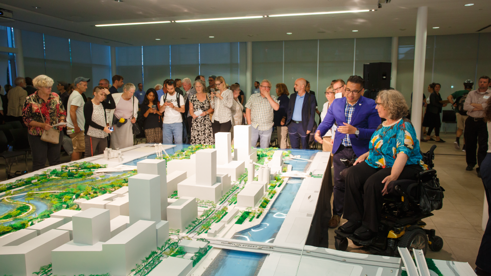A person in a mobility chair looking at model of the Port Lands at a public event. 