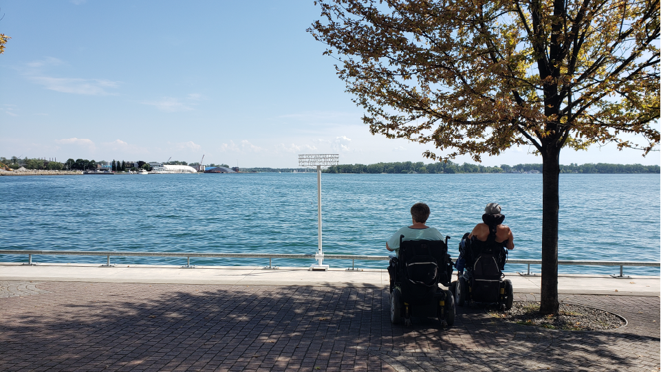 Two people using mobility devices looking out at Toronto Harbour. 