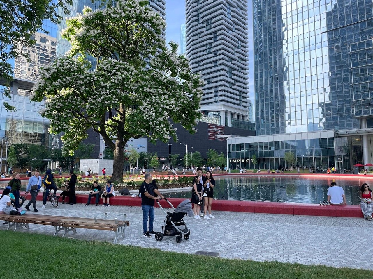 people next to a red heart shaped pond in an urban park