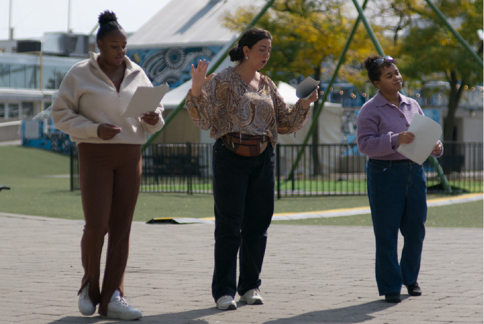 Three actors rehearsing a scene outdoors.