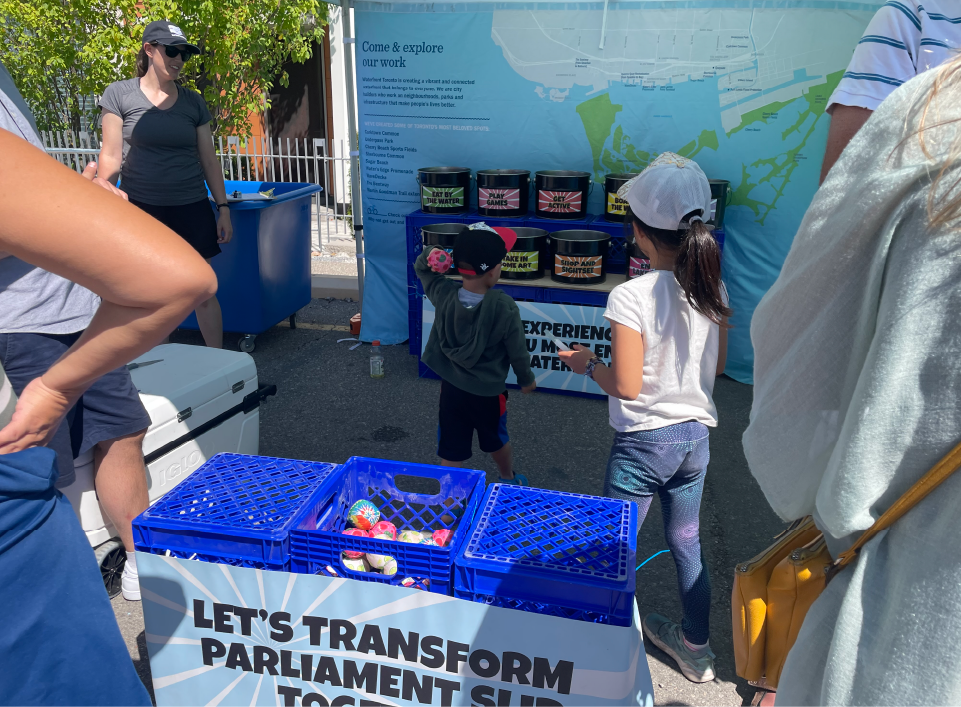 Children playing a ball-toss game at a summer festival.