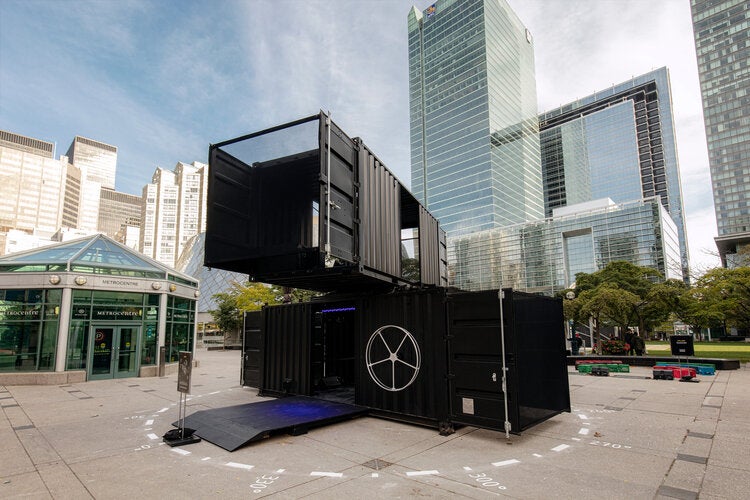 A modular rotating shipping container set up in a public event space.