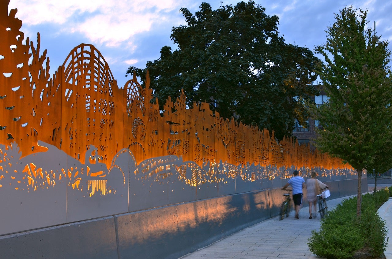 Two individuals walking past the artwork Site Specific with their bikes. 