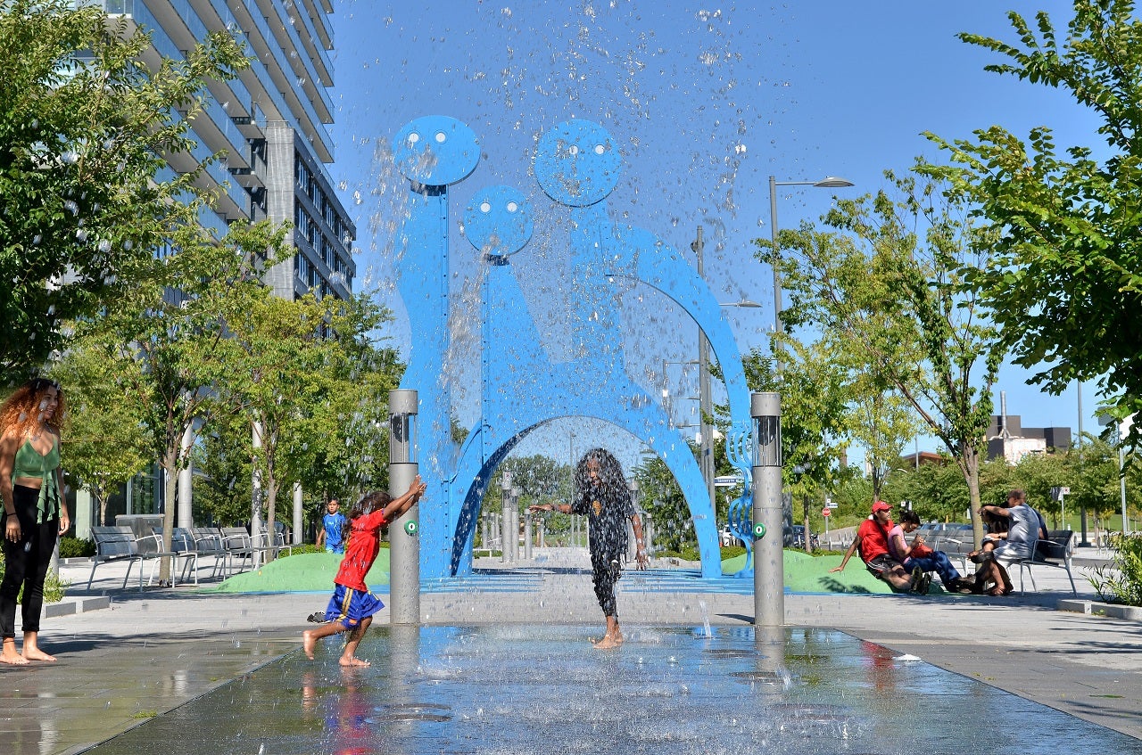 The Water Guardians public art on Front Street Promenade with children playing with the water feature.
