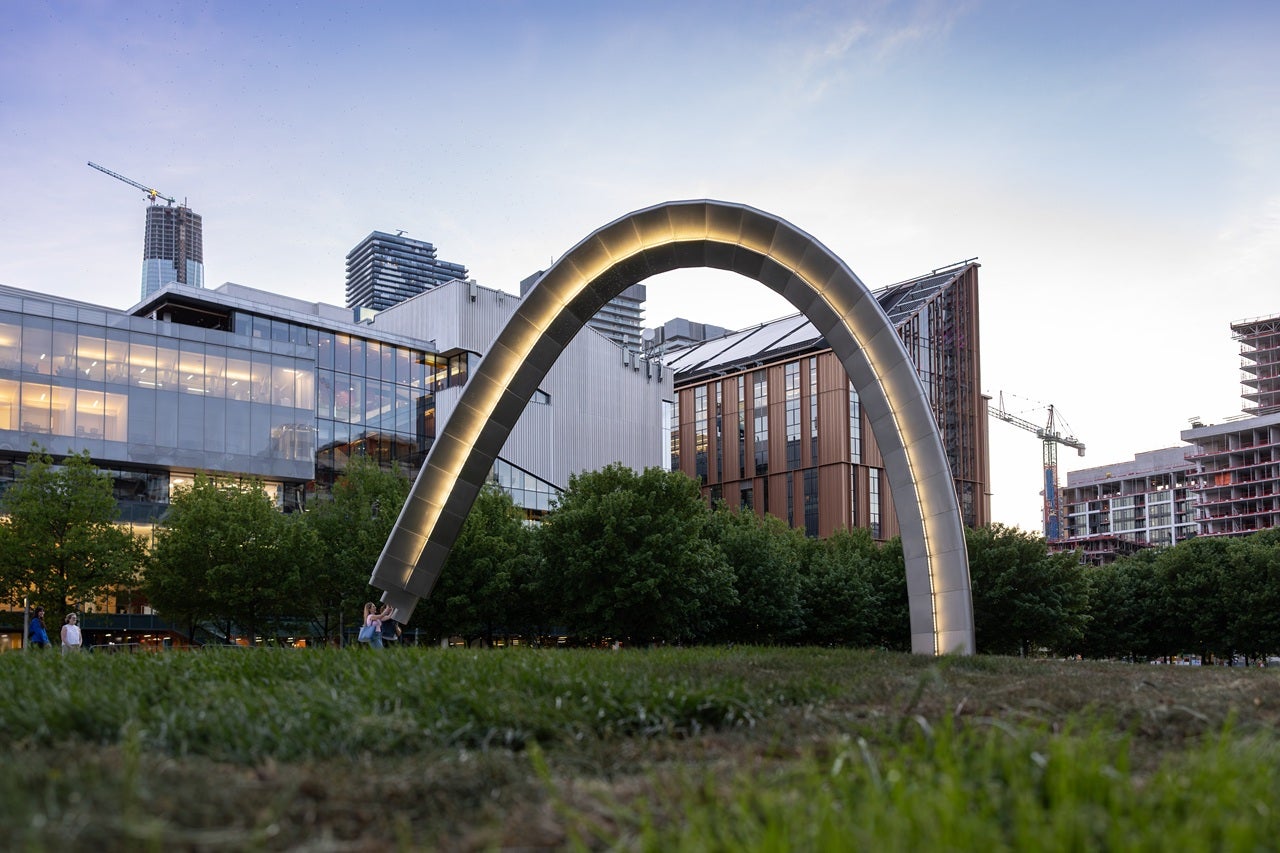 A view of Unfinished Arch art piece lit up at dusk.