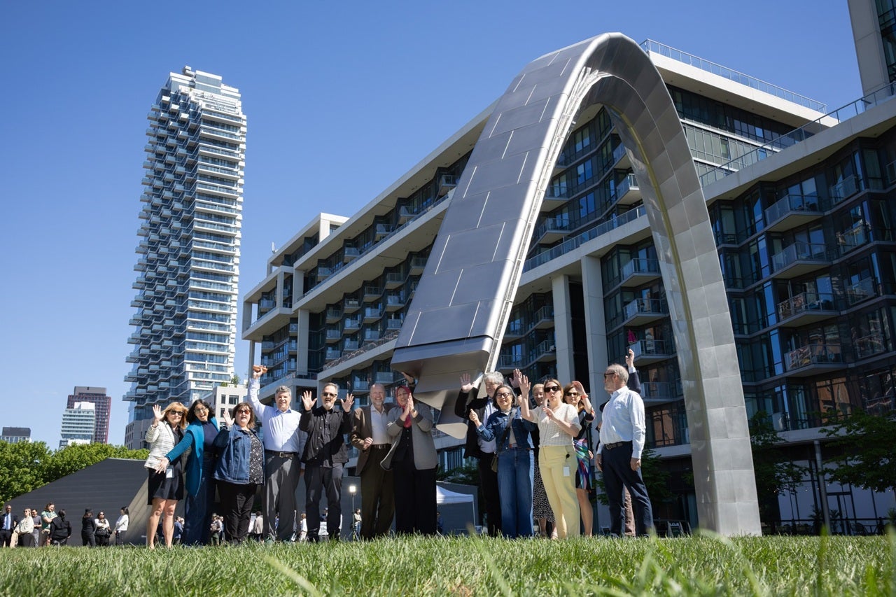 A group of people pose in front of a new public art installation in a park.