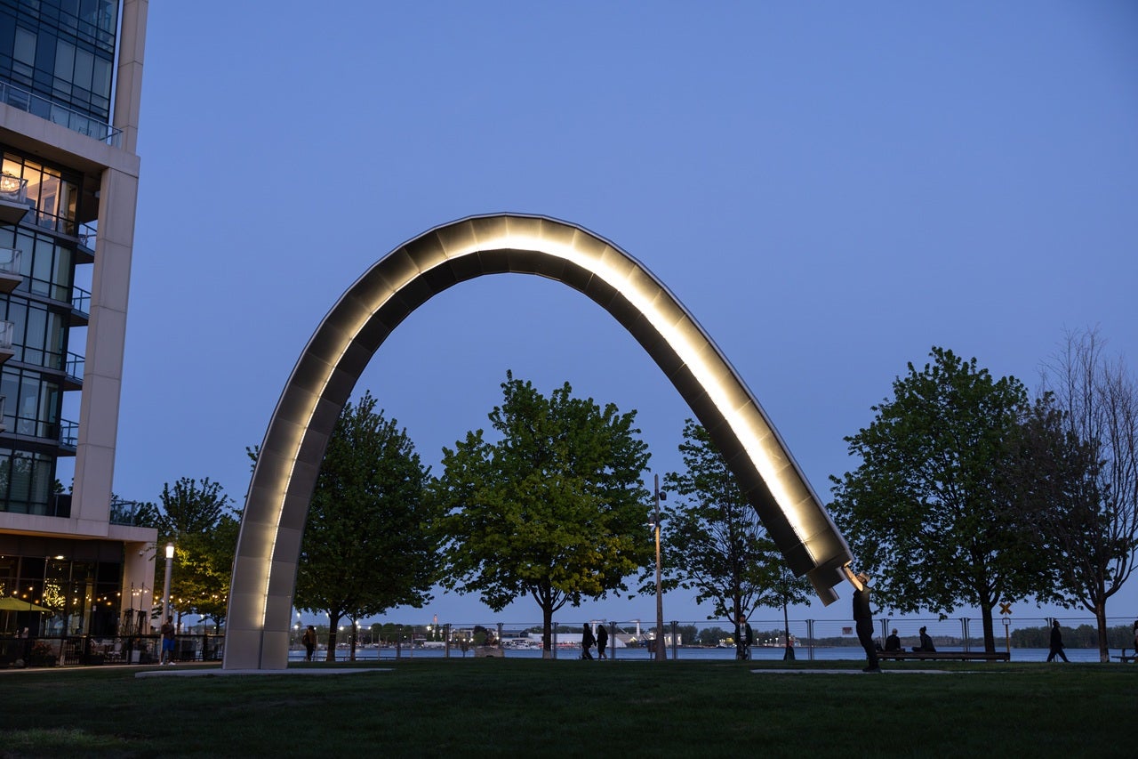 A large public art arch is activated by the artist and lit up at night