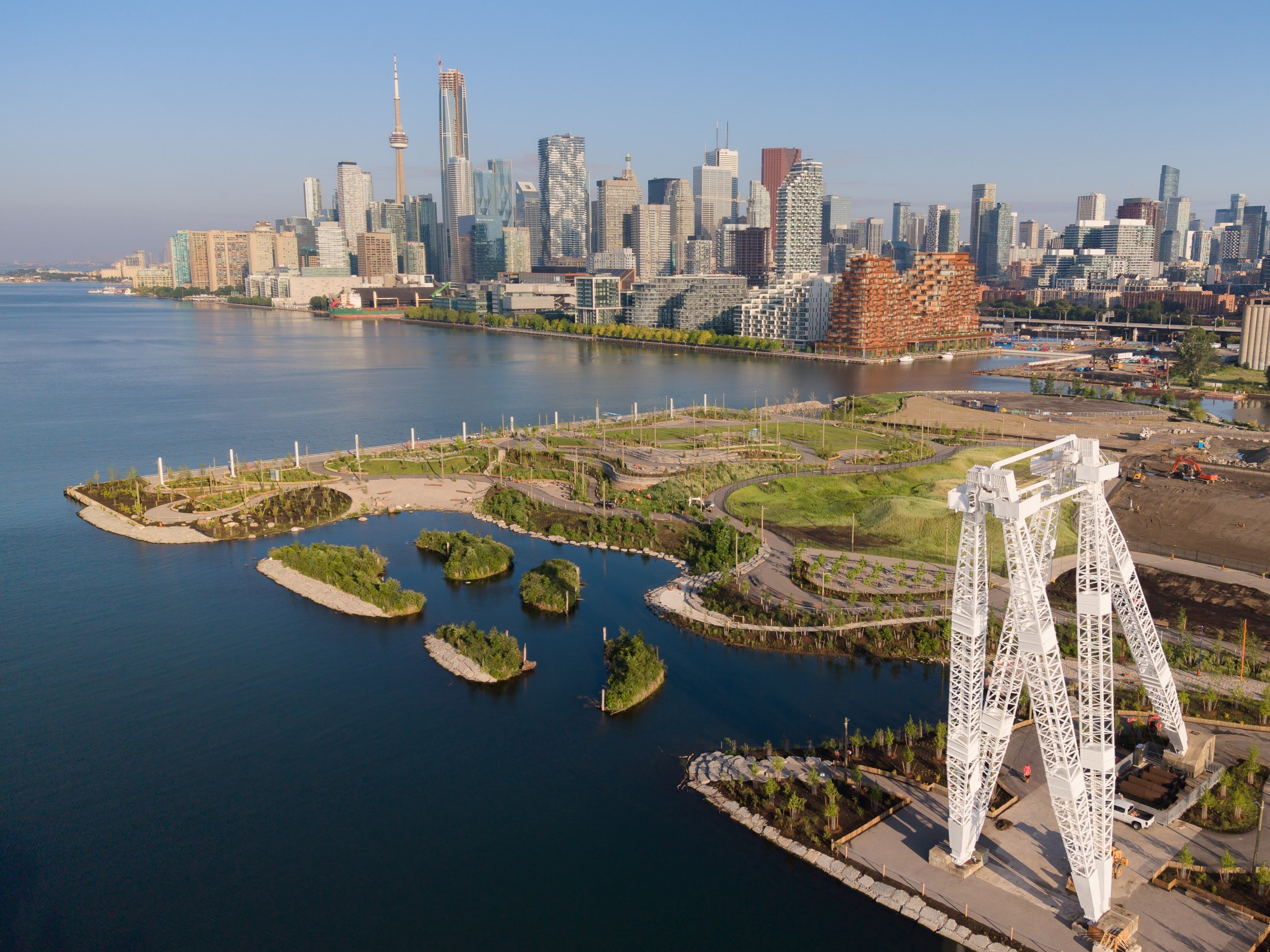 Aerial view of Biidaasige Park featuring wetlands, trails, and the restored Canada Malting silos, with Toronto’s skyline and the CN Tower in the background.