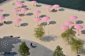 rooftop view showing a sandy beach with pink umbrellas