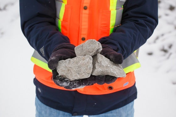a person in construction gear holding three large rocks in their hands
